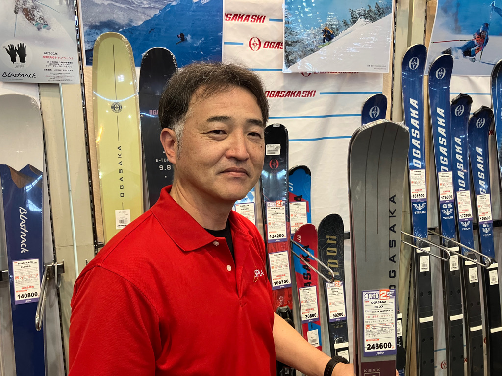 総責任者の赤堀さん。手に持つのは職人が1本1本丁寧に仕上げているというスキー板。お値段約25万円だが全国で品薄だという