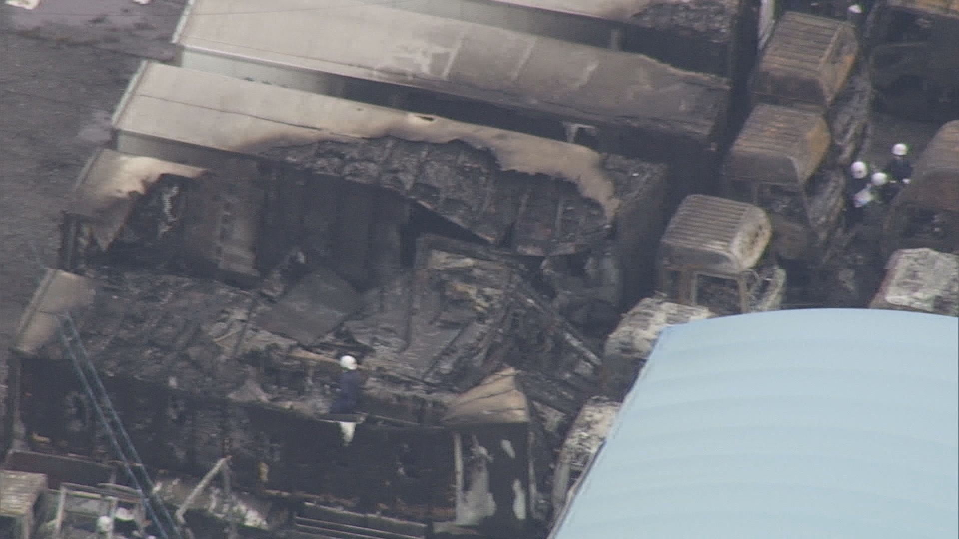 焼けた車両を調べる警察官